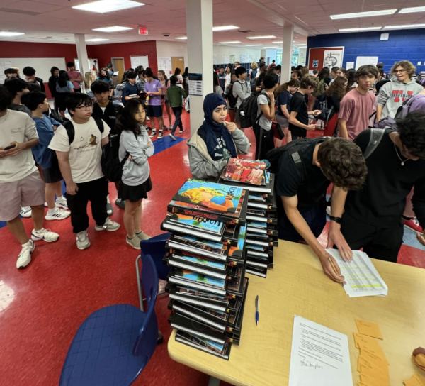 Lining up, students receive their yearbooks at Turing Commons. Yearbook purchases came with a complimentary addition of the Teknos and Threshold journals. “I worked on the yearbook team as an editor,” sophomore Kimberly Cruz-Cruz said. “It felt surreal handing out our year’s worth of work.”